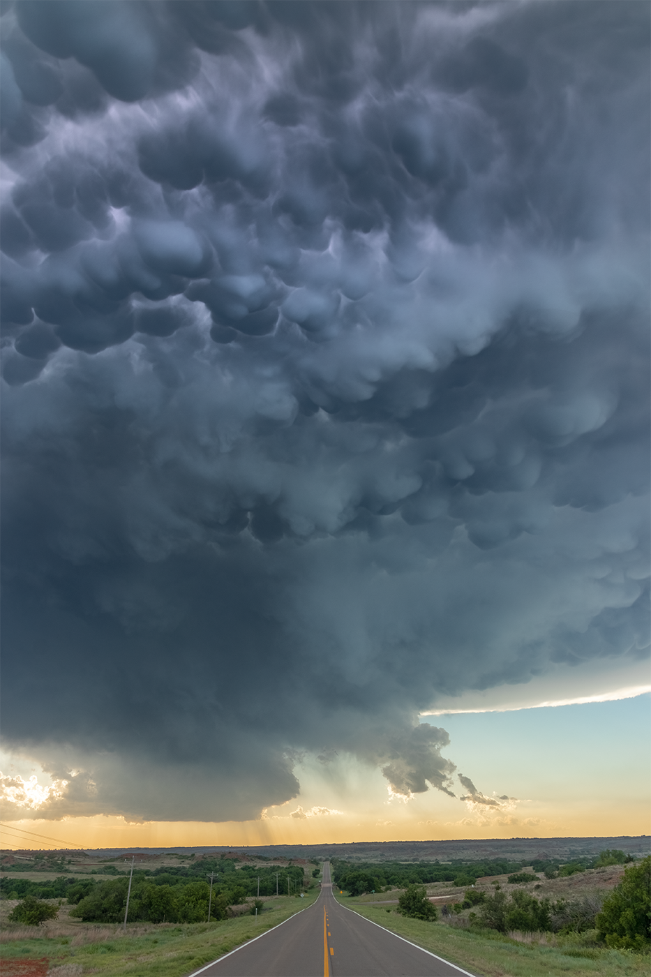 A sublime mammatus display hangs low over the road from an Oklahoma supercell.