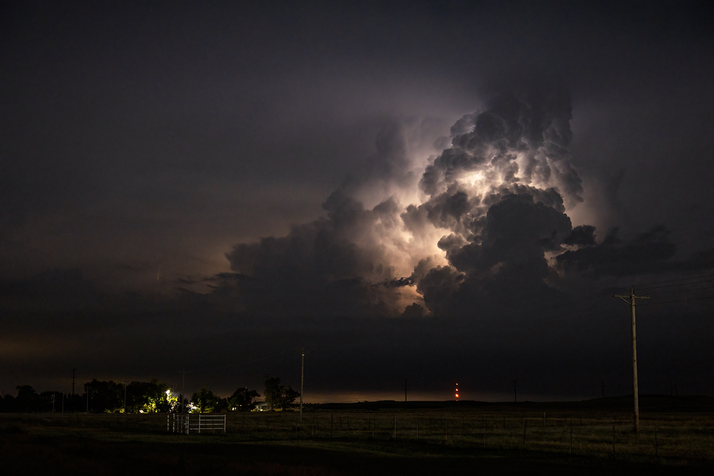 Lightning illuminates the updraft of a thunderstorm over a farmstead near Dodge, KS