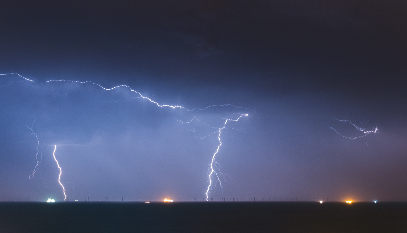 Multiple lightning strikes at night from a storm complex over an offshore windfarm in the English Channel.