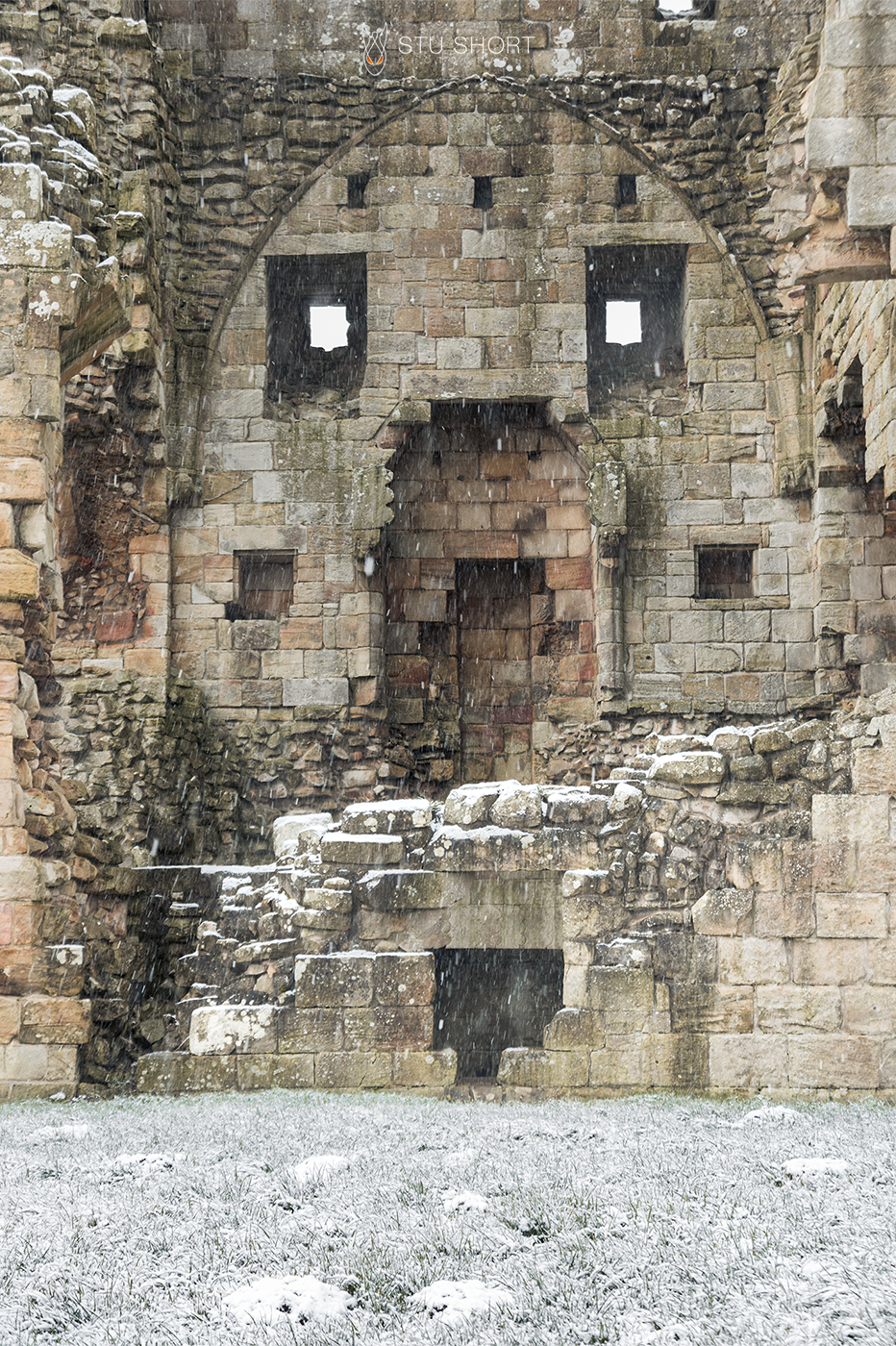 The internal ruins of Edlingham Castle appear to form a face as snow falls around it.