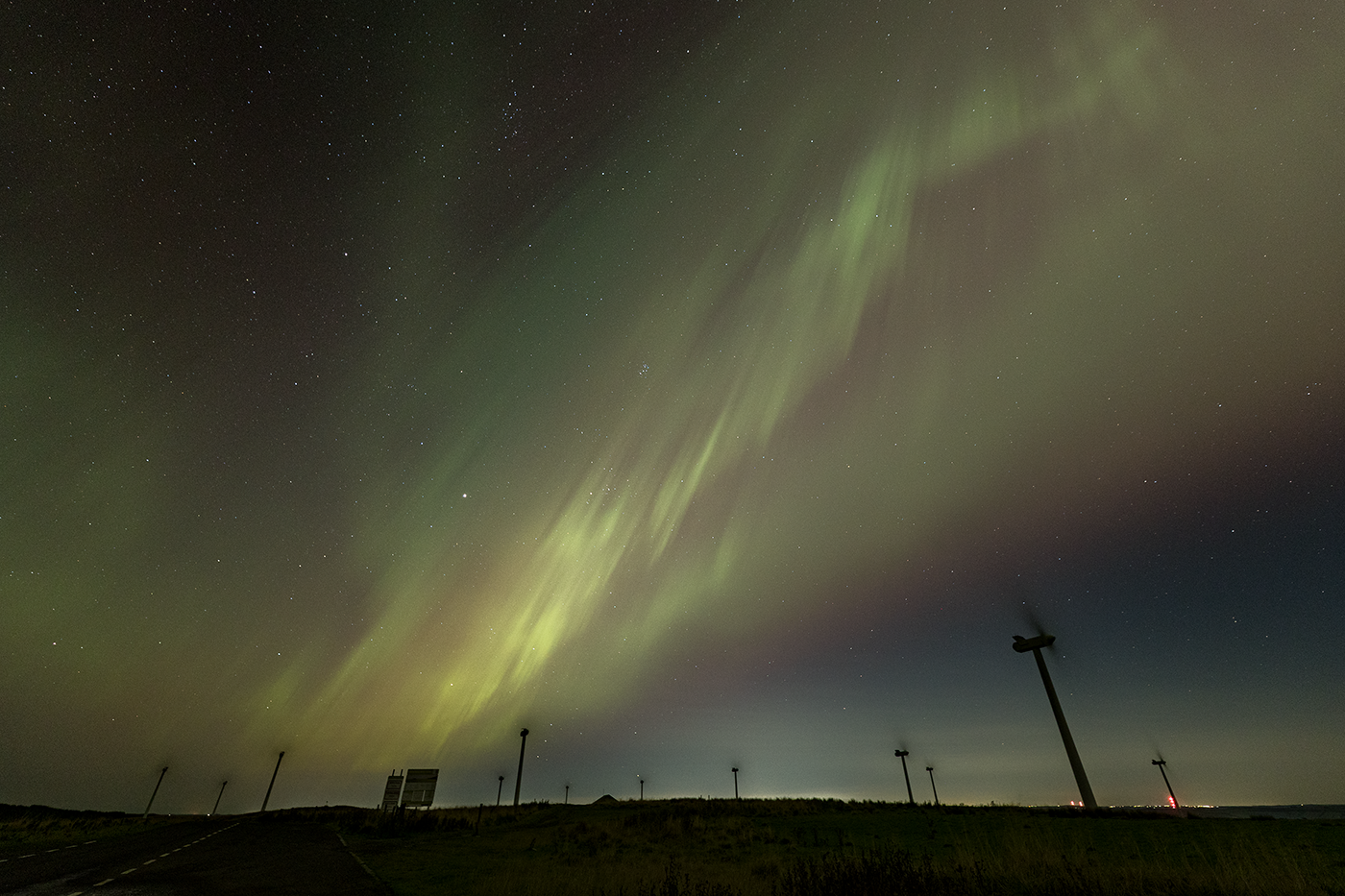 Vibrant green ribbons form above a windfarm as part of a powerful Northern Lights display.