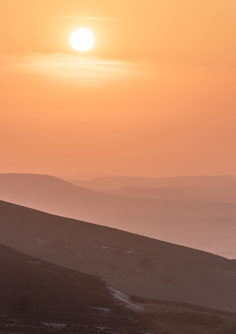 Golden sunrise over a landscape of misty hills and valleys.