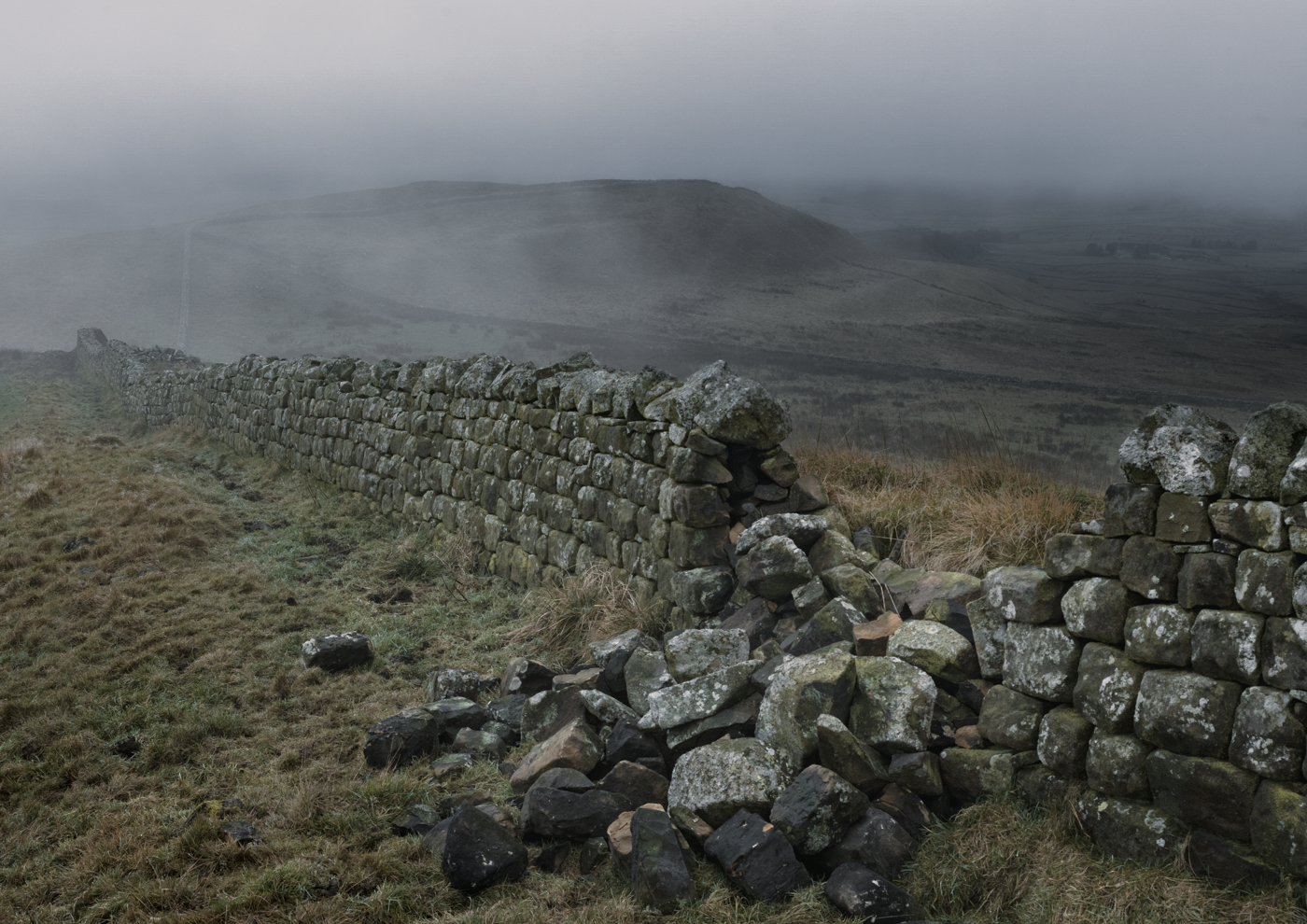 Hadrian's Wall in Northumberland, England, on a misty day.