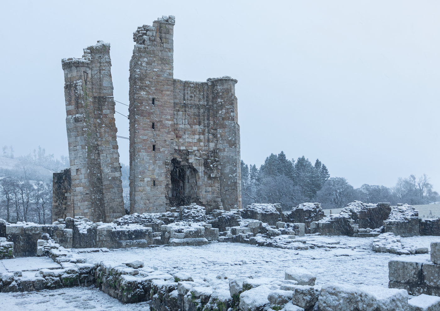 Snow-covered ruins of Edlingham Castle in a winter landscape