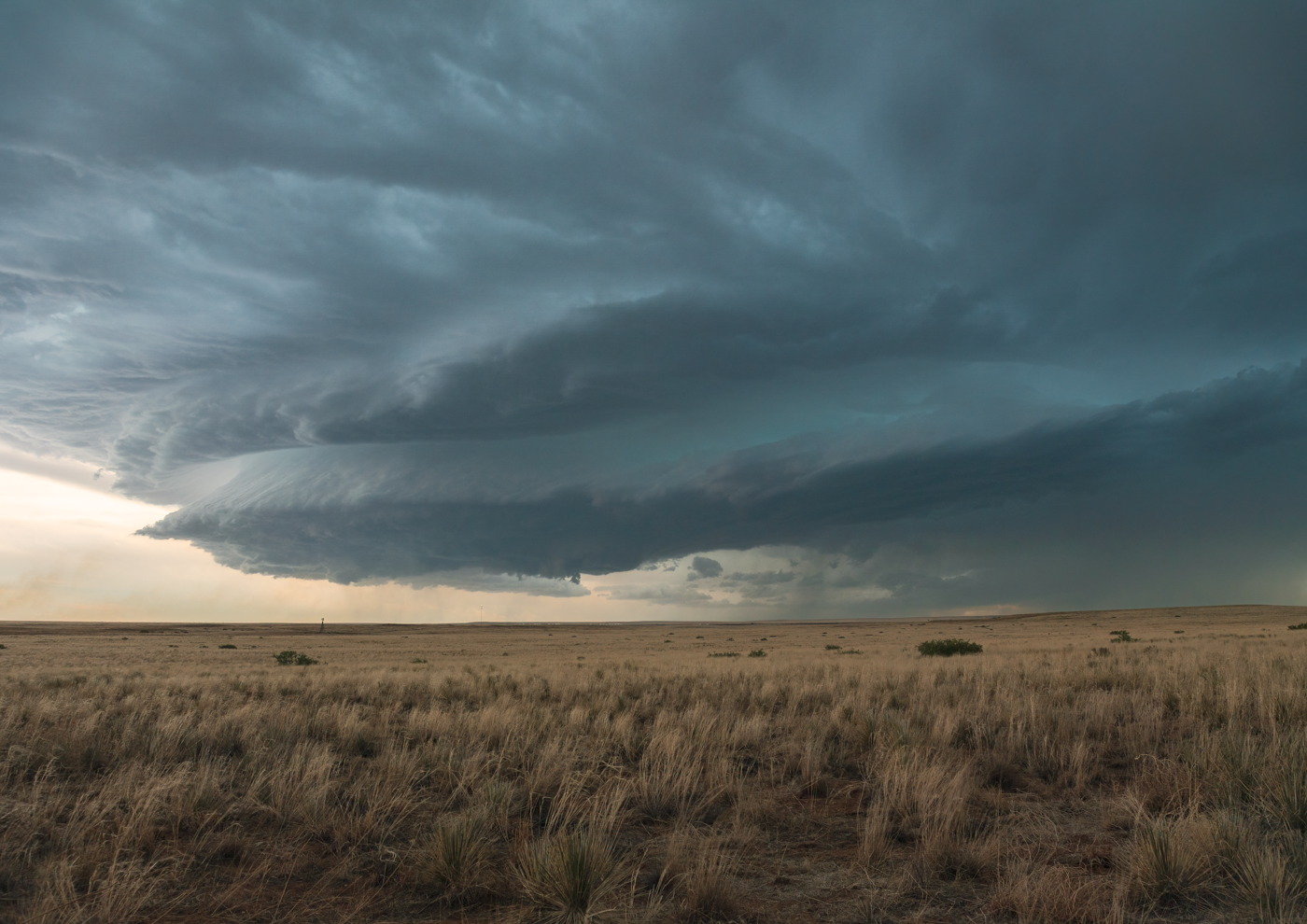 Massive supercell storm cloud with swirling formations over a flat plain.