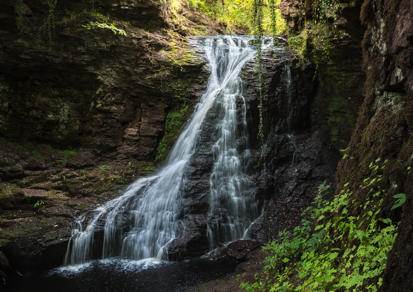 Waterfall cascading over moss-covered rocks in a forest.