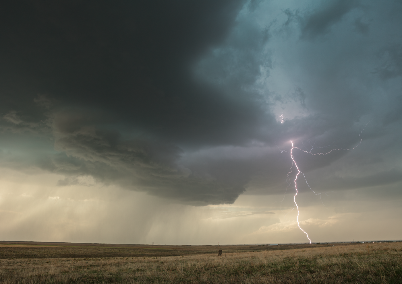 Lightning strikes illuminating a stormy sky over a vast plain.