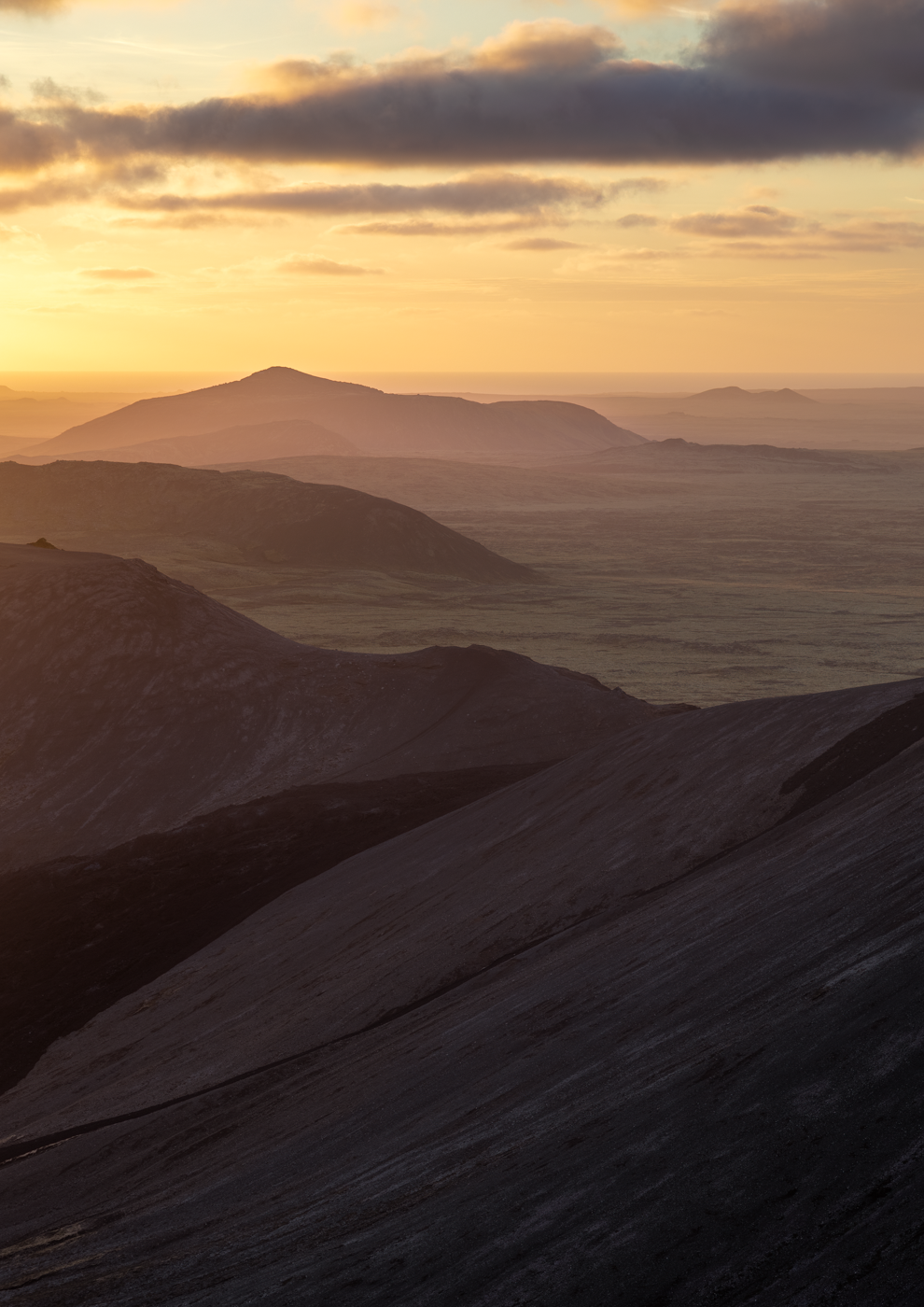 Golden sunset over layers of Iceland's hilly landscape..