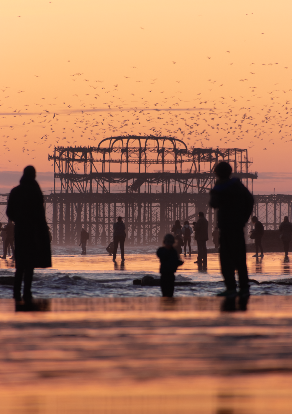 Pier extending into a misty sea at low tide.