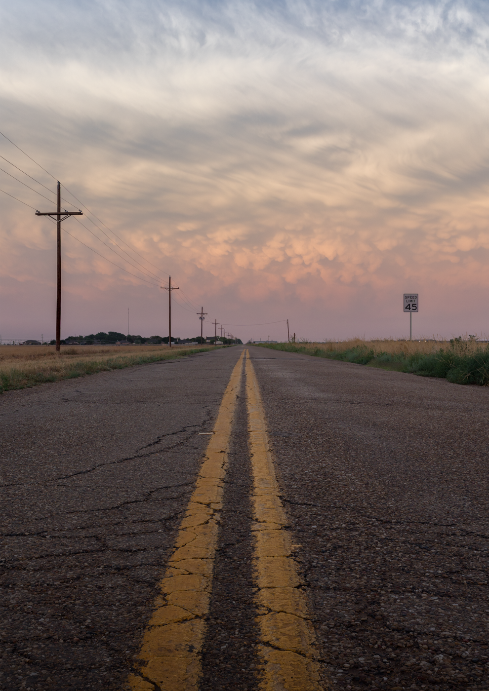 Road stretching towards a dramatic sky with mammatus clouds.