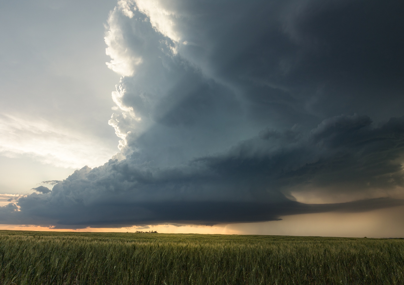 Dark storm cloud looming over a field with dramatic lighting.