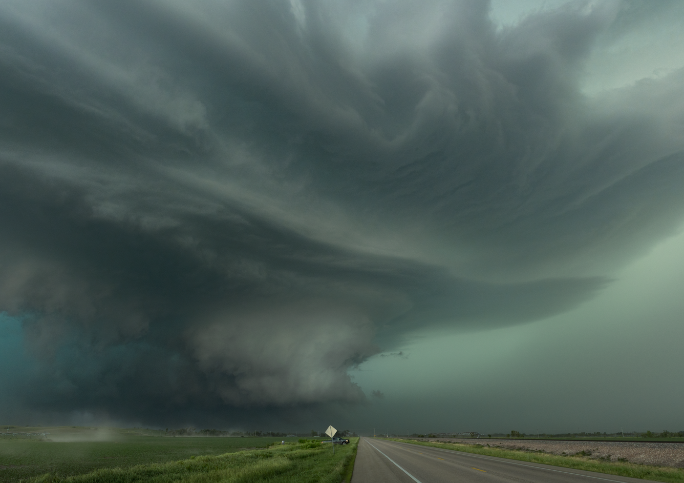 Massive supercell storm cloud with a rotating updraft base over the highway.