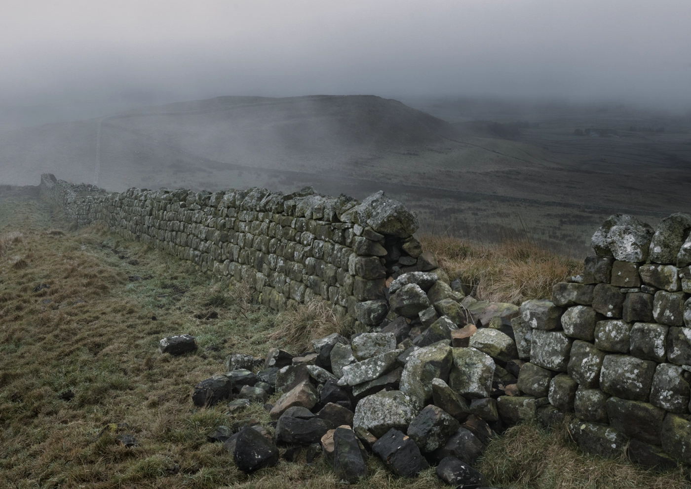 Hadrian's Wall in Northumberland, England, on a misty day.